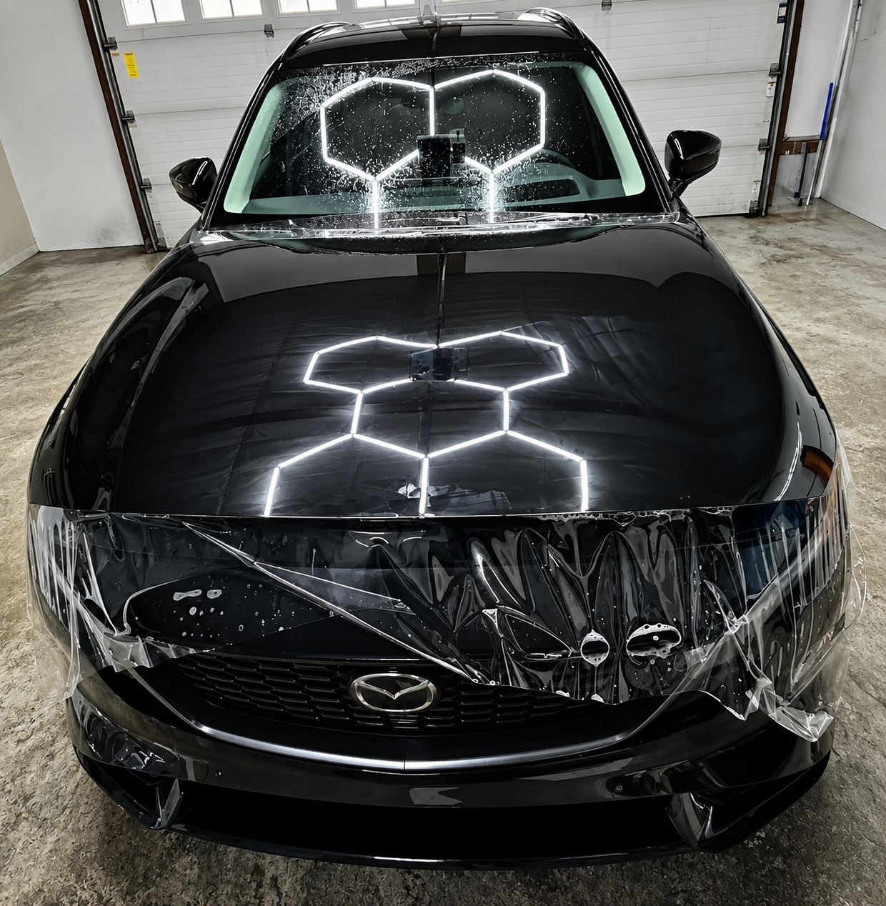 Black Mazda SUV front end wrapped in clear paint protection film in the shop